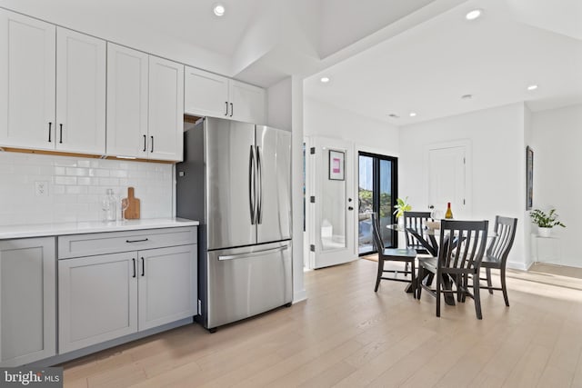 kitchen featuring gray cabinets, white cabinetry, stainless steel fridge, decorative backsplash, and light hardwood / wood-style flooring