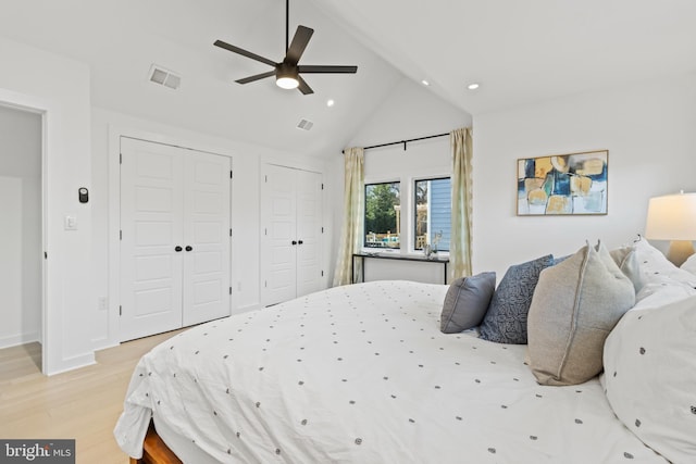 bedroom with multiple closets, ceiling fan, lofted ceiling, and light hardwood / wood-style floors