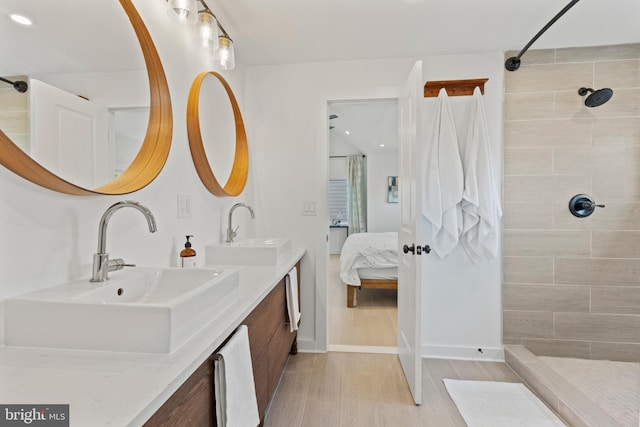 bathroom with hardwood / wood-style flooring, vanity, and tiled shower