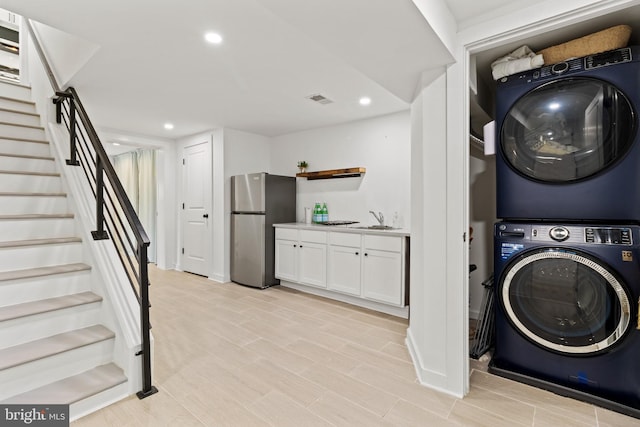 clothes washing area featuring sink and stacked washing maching and dryer