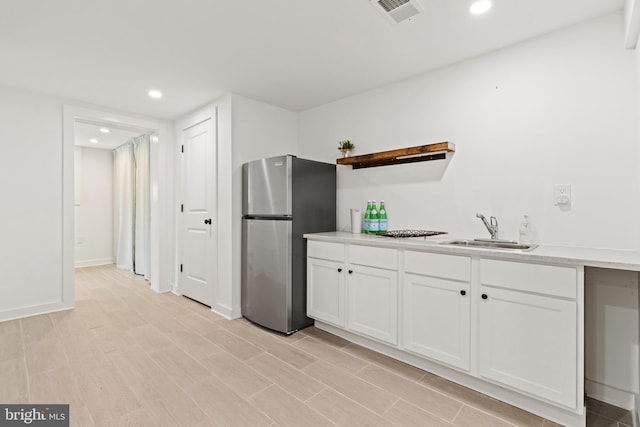 kitchen with sink, light hardwood / wood-style floors, stainless steel refrigerator, and white cabinets