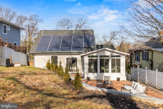 rear view of house featuring a patio area, a sunroom, and solar panels