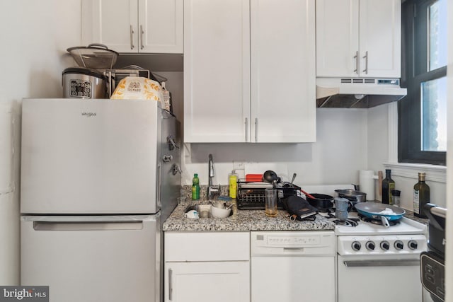 kitchen with light stone countertops, white appliances, white cabinetry, and sink