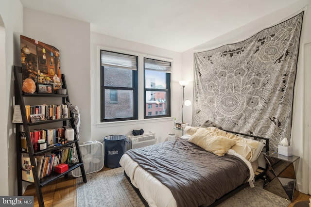 bedroom with hardwood / wood-style flooring and a wall unit AC