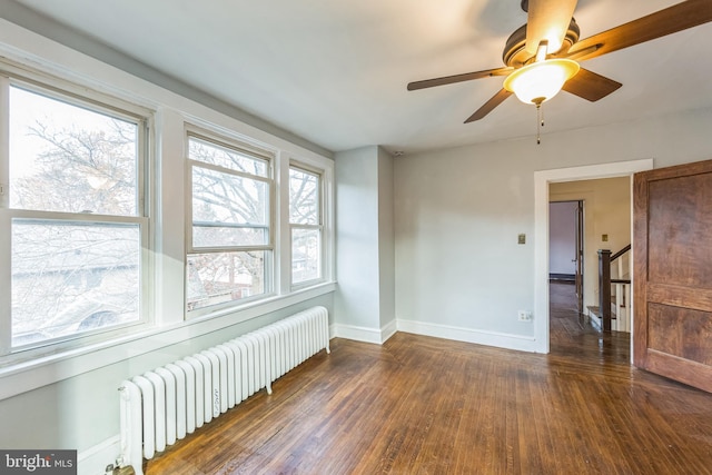 unfurnished room with ceiling fan, dark hardwood / wood-style flooring, and radiator heating unit