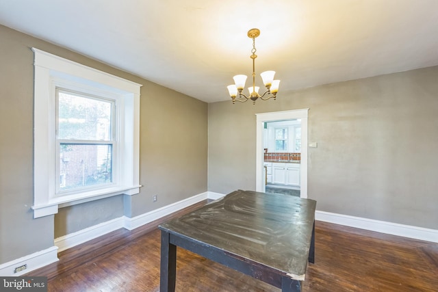 unfurnished dining area with dark wood-type flooring and a notable chandelier