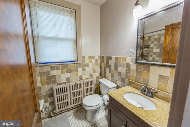 bathroom with vanity, radiator, tile patterned floors, toilet, and tile walls