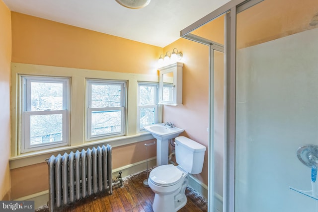 bathroom with radiator heating unit, hardwood / wood-style flooring, toilet, and walk in shower