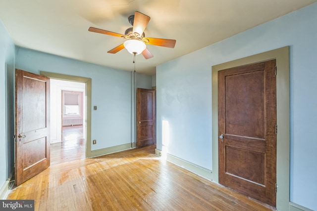 unfurnished bedroom with ceiling fan, radiator heating unit, and light hardwood / wood-style flooring