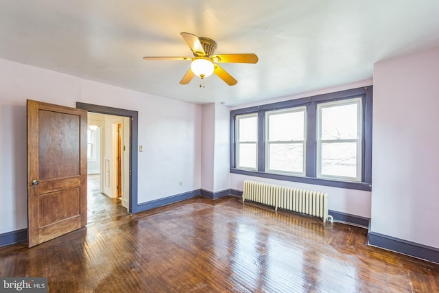 spare room featuring radiator heating unit, dark hardwood / wood-style flooring, and ceiling fan