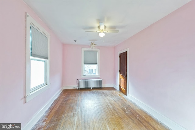 spare room featuring radiator, ceiling fan, and light wood-type flooring