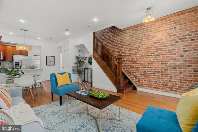 living room with sink, light wood-type flooring, and brick wall