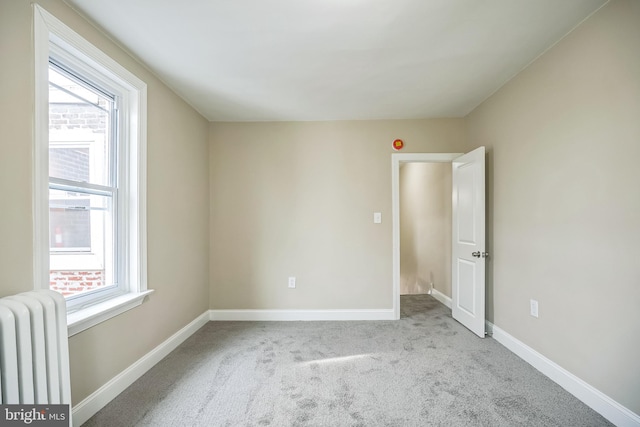 empty room featuring light colored carpet and radiator