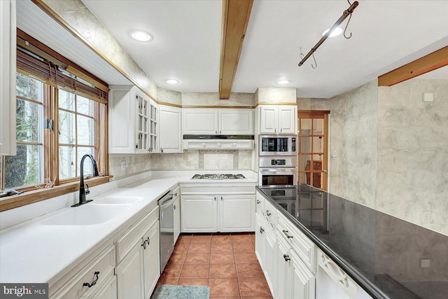 kitchen with white cabinets, beam ceiling, sink, and stainless steel appliances