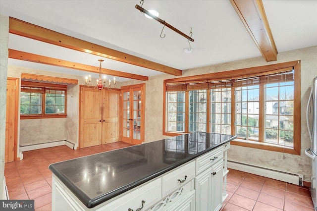 kitchen with white cabinets, plenty of natural light, baseboard heating, and hanging light fixtures