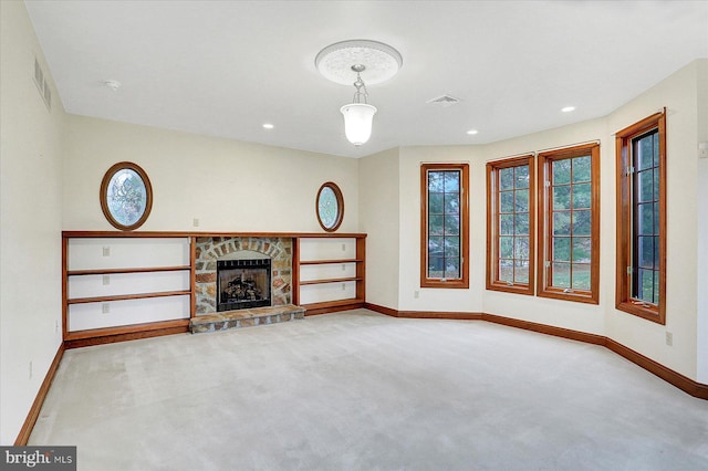 unfurnished living room featuring a stone fireplace and light carpet