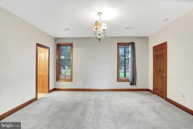 spare room with light carpet and an inviting chandelier