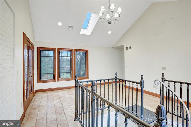 hall with a chandelier, a skylight, and high vaulted ceiling