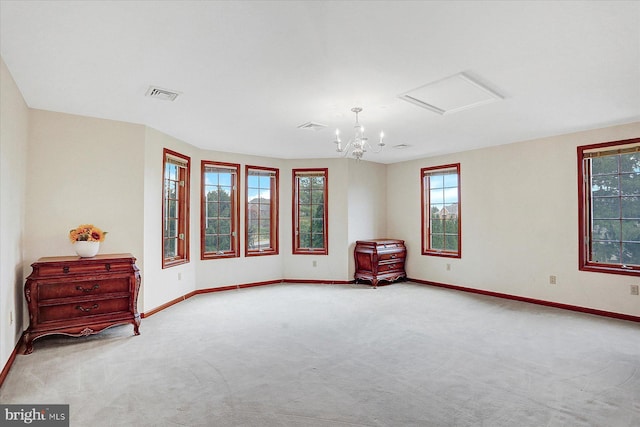 empty room featuring a notable chandelier, a healthy amount of sunlight, and light carpet