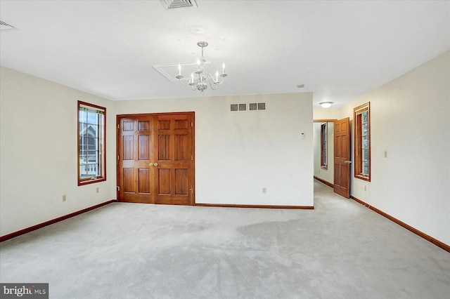 carpeted spare room featuring an inviting chandelier