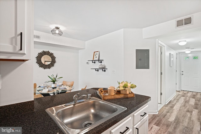 kitchen with white cabinets, sink, electric panel, and light hardwood / wood-style flooring