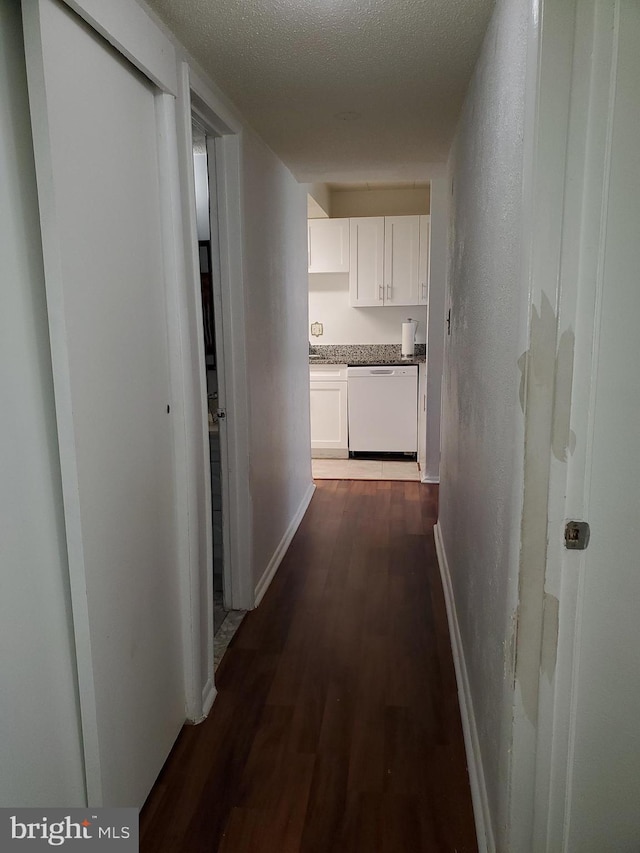 hall with dark hardwood / wood-style flooring and a textured ceiling