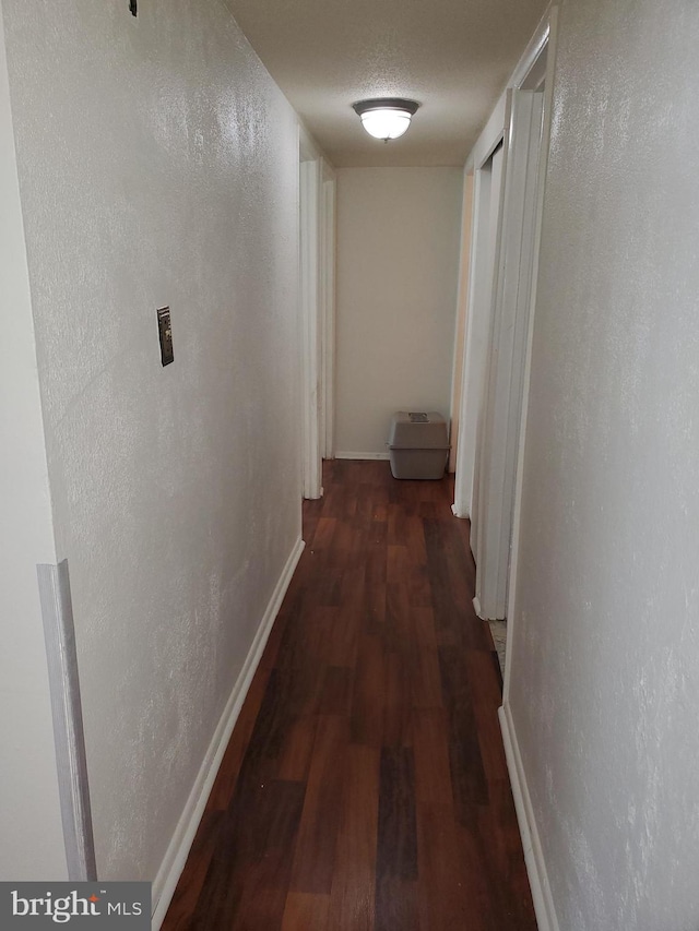 corridor with dark wood-type flooring and a textured ceiling