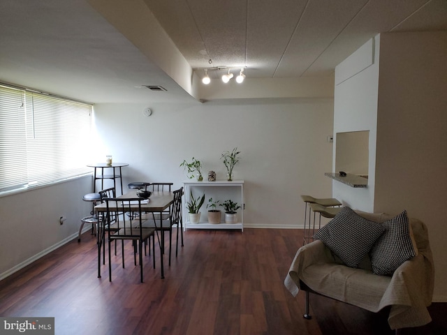 dining area featuring rail lighting and dark hardwood / wood-style floors