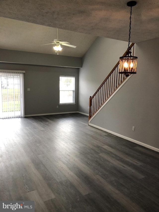 interior space with ceiling fan with notable chandelier, a textured ceiling, dark hardwood / wood-style flooring, and vaulted ceiling