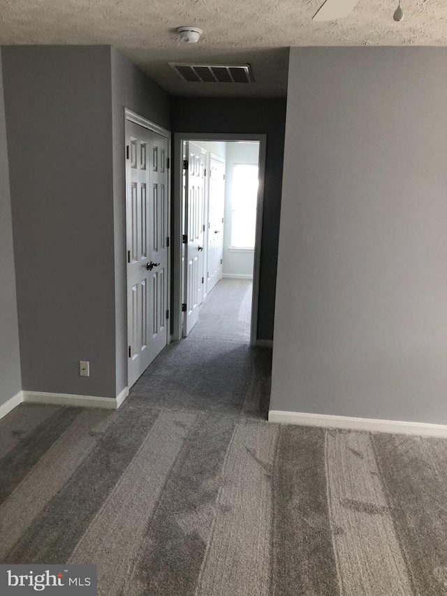 corridor with carpet flooring and a textured ceiling