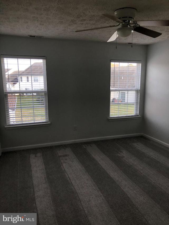 carpeted spare room with ceiling fan and a textured ceiling