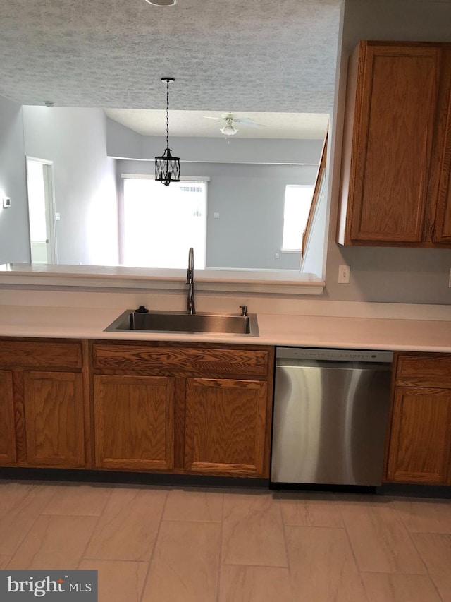 kitchen with stainless steel dishwasher, ceiling fan with notable chandelier, a textured ceiling, sink, and hanging light fixtures