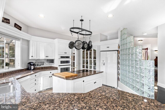 kitchen with white cabinetry, dark stone counters, recessed lighting, and white appliances