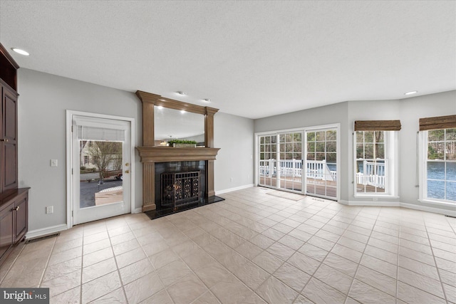 unfurnished living room with a large fireplace, light tile patterned flooring, baseboards, and a textured ceiling