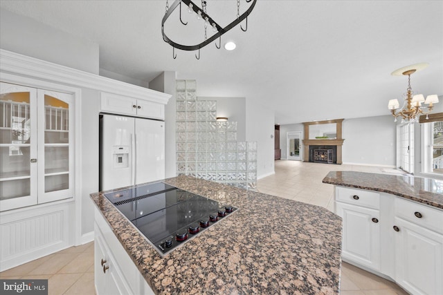 kitchen with an inviting chandelier, light tile patterned flooring, white fridge with ice dispenser, and black electric stovetop