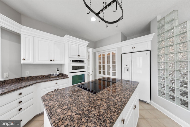 kitchen with light tile patterned flooring, white cabinets, white appliances, a kitchen island, and french doors