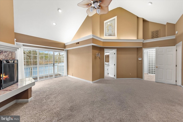 unfurnished living room featuring high vaulted ceiling, a lit fireplace, carpet, baseboards, and ceiling fan