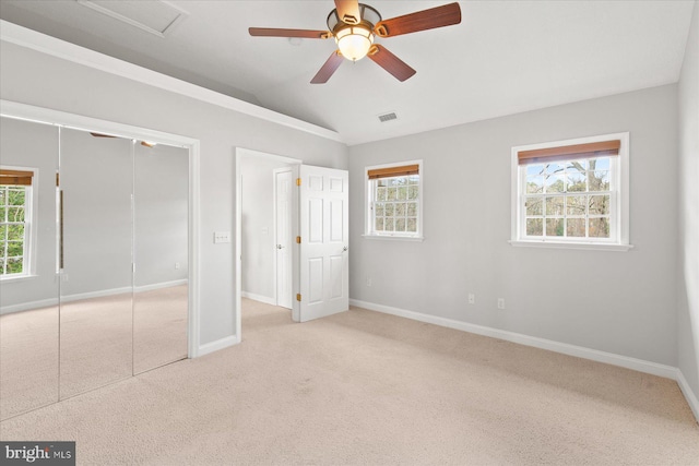 unfurnished bedroom featuring light colored carpet, baseboards, vaulted ceiling, and visible vents