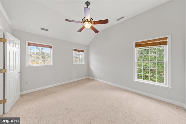 carpeted empty room featuring baseboards, ceiling fan, visible vents, and vaulted ceiling