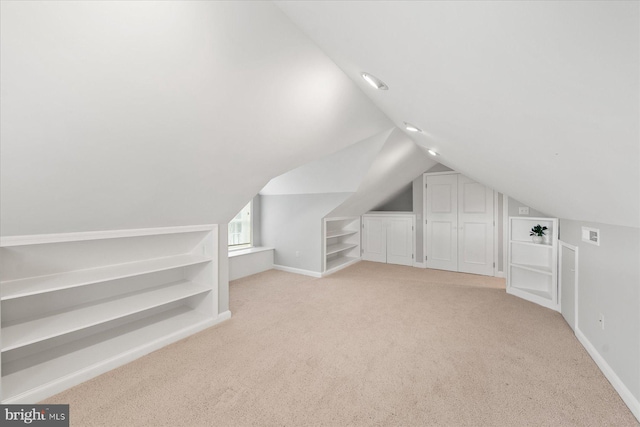 bonus room with baseboards, lofted ceiling, light colored carpet, and built in shelves