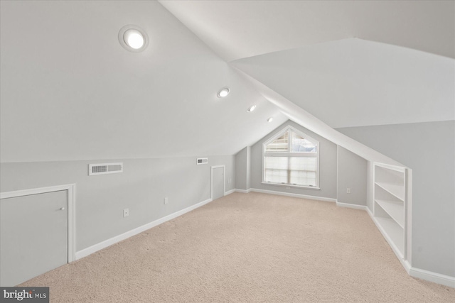 additional living space featuring baseboards, carpet floors, lofted ceiling, and visible vents