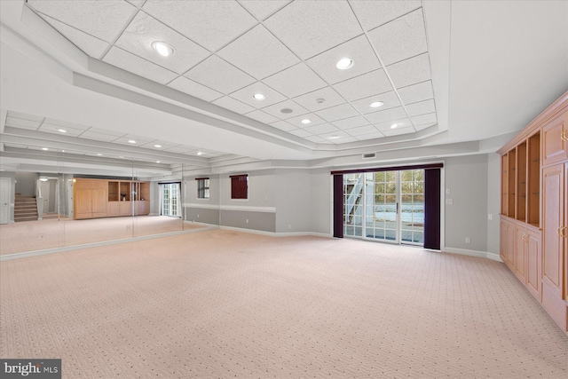 unfurnished living room featuring a raised ceiling, baseboards, light colored carpet, and recessed lighting