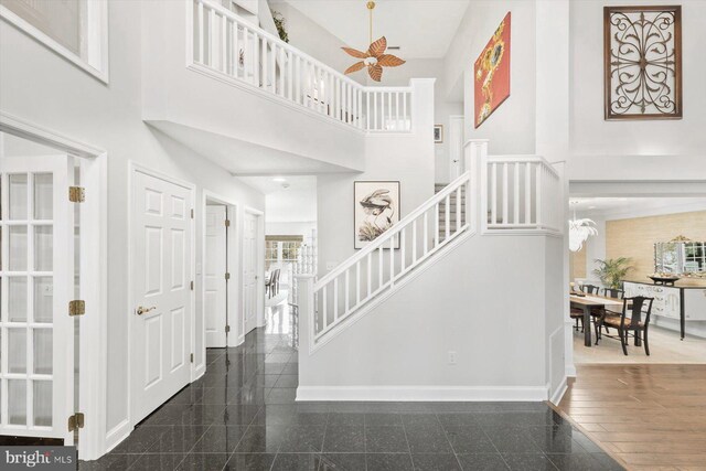 entryway with baseboards, stairs, ceiling fan, granite finish floor, and a high ceiling