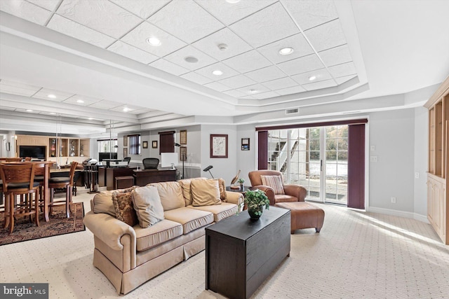 living area with light carpet, a tray ceiling, baseboards, and visible vents