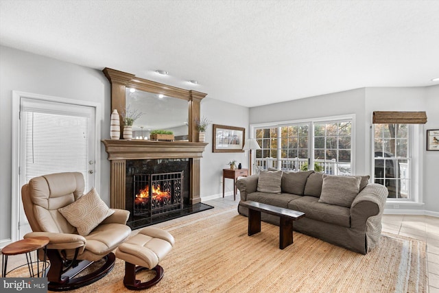 living room with baseboards, a textured ceiling, and a premium fireplace