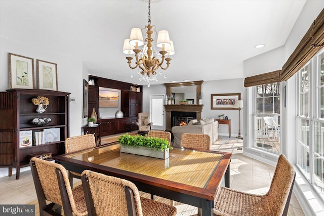 dining area with a warm lit fireplace, recessed lighting, light tile patterned floors, and a chandelier
