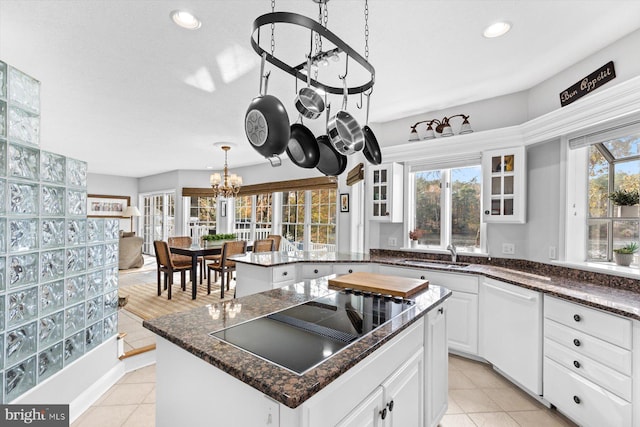 kitchen featuring glass insert cabinets, white dishwasher, black electric stovetop, and light tile patterned floors