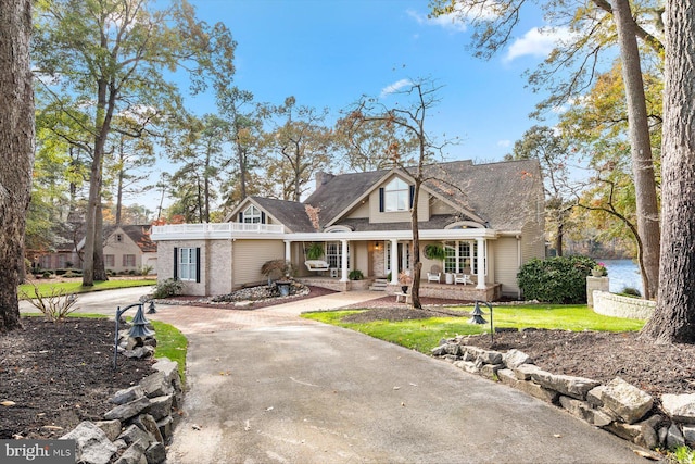 view of front of house featuring a porch, driveway, and a front lawn