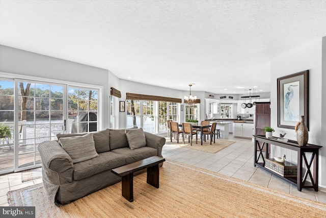 living room with a textured ceiling, an inviting chandelier, and light tile patterned floors