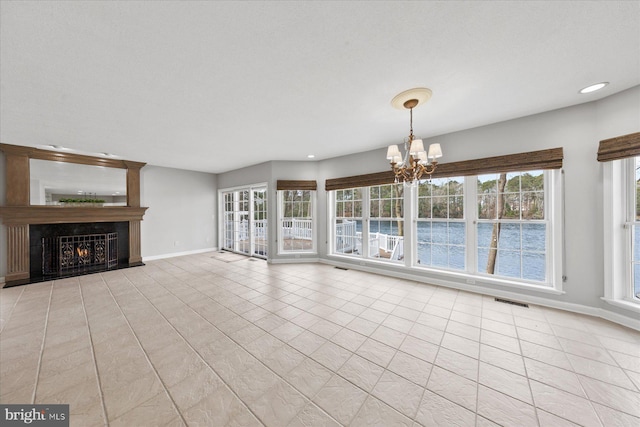 unfurnished living room featuring recessed lighting, baseboards, visible vents, a warm lit fireplace, and a notable chandelier